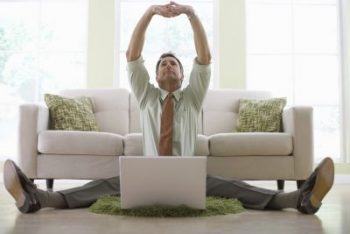 Businessman Stretching While Working on His Laptop --- Image by © Royalty-Free/Corbis